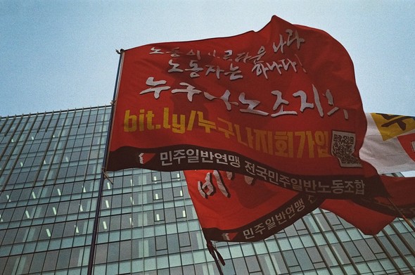 마천루를 배경으로 붉은 누구나지회 깃발이 휘날리고 있다.