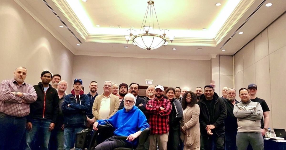 A large group posing in a hotel beige conference room