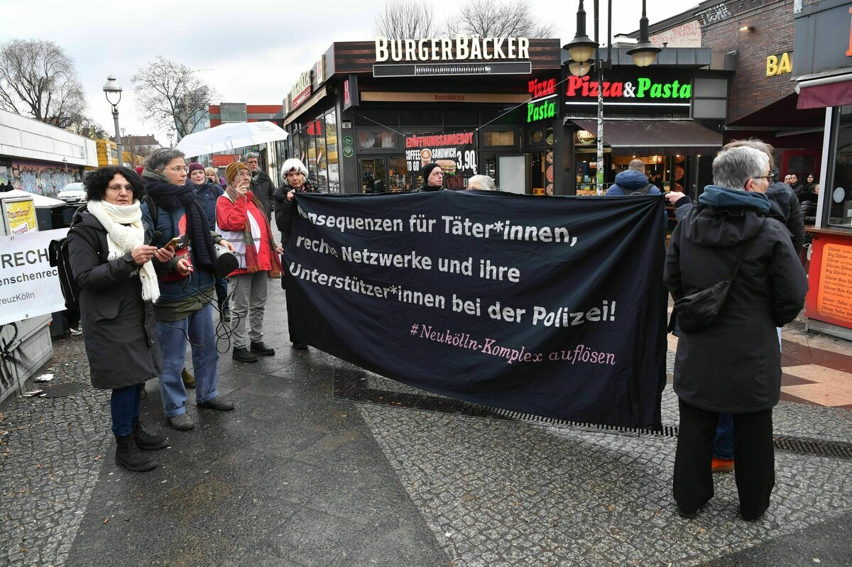Teilnehmende einer Mahnwache halten im Stadtteil Neukölln ein Transparent mit dem Aufdruck „Konsequenzen für Täter*innen, rechte Netzwerke und ihre Unterstützer*innen bei der Polizei! #Neukölln-Komplex auflösen“.