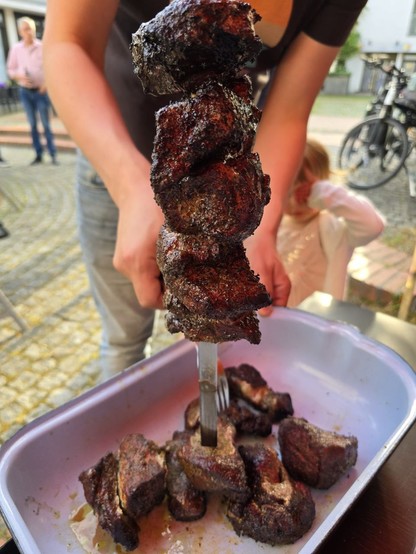 Die schön gegrillten Mutzbraten Stücke werden von einem Spieß geschoben und in einer Form abgelegt.