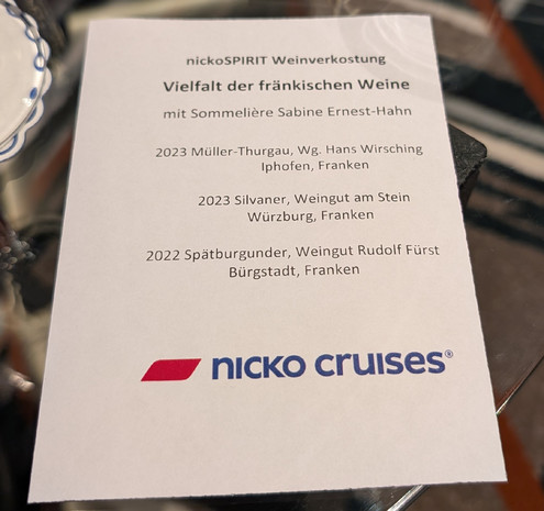 Ein Zettel mit den Details zu drei fränkischen Weinen und dem Namen der Sommelière, die die Weinprobe moderieren wird. 