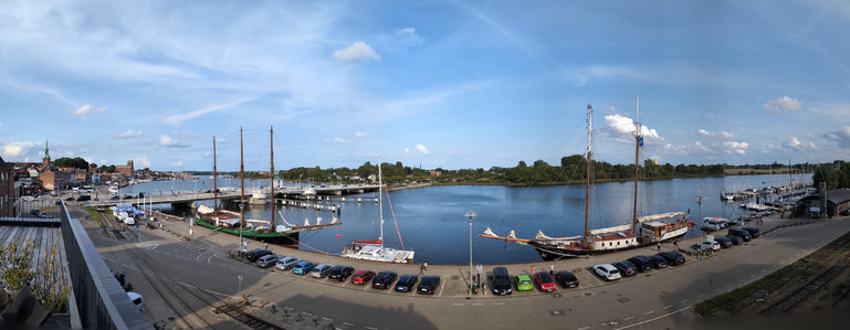 Panoramaaufnahme des Hafens von Kappeln von der Dachterrasse unserer Ferienwohnung. Schlei, Schiffe, Brücke unter blauem Himmel mit ein paar Wölkchen. 