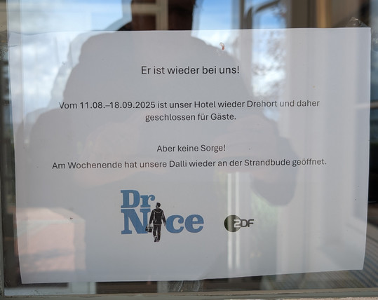 Ein Zettel klebt an der Eingangstür des Hotels und informiert darüber, dass das ZDF bis zum 18. September hier für die Serie Dr. Nice dreht. 