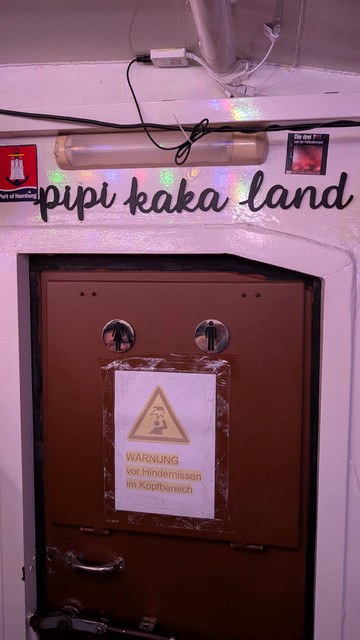Schrift über der Tür zum Klo auf der Hafenbarkasse: "Pipi Kaka Land". 