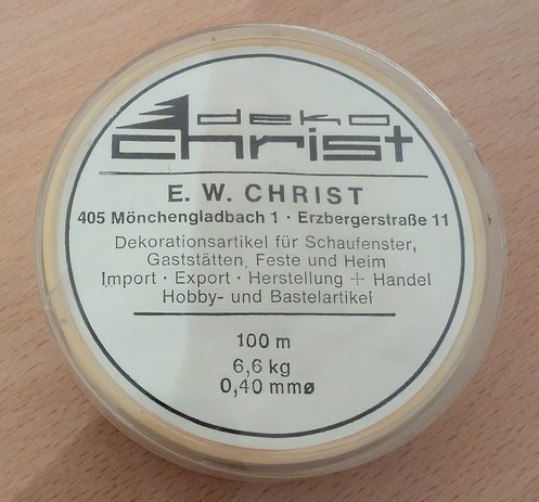 Rückseite einer Dose mit Nylonschnur. Die Adresse des Geschäfts ist mit dreistelliger Postleitzahl angegeben.