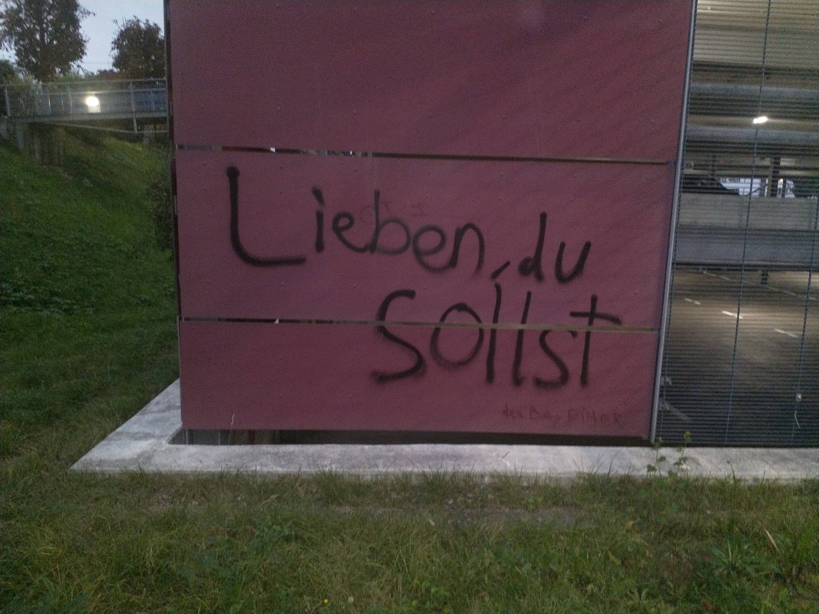 etwas ungelenkes Graffitti an einem Parkhaus mit dem Text "Lieben, du sollst"