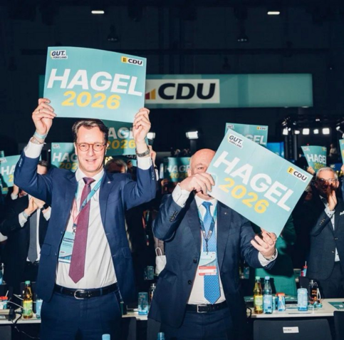 CDUler halten bei Parteiveranstaltung Plakate mir "Hagel 2026" hoch.