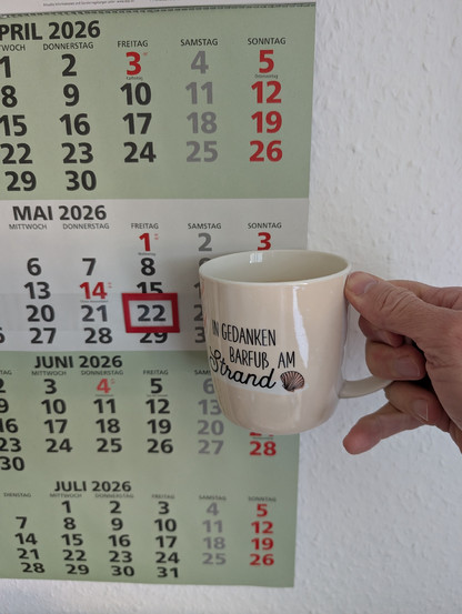 3 Monatskalender mit heutigem Datum. Ich halte eine Kaffeetasse davor. 