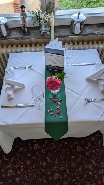 Gedeckter Tisch mit Blümchen und kleinen roten Stoffherzen.