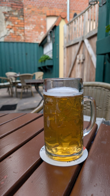 Ein Bierseidel 0,5 Liter mit Schulzens Hell auf dem Tisch im Biergarten der Brauerei.