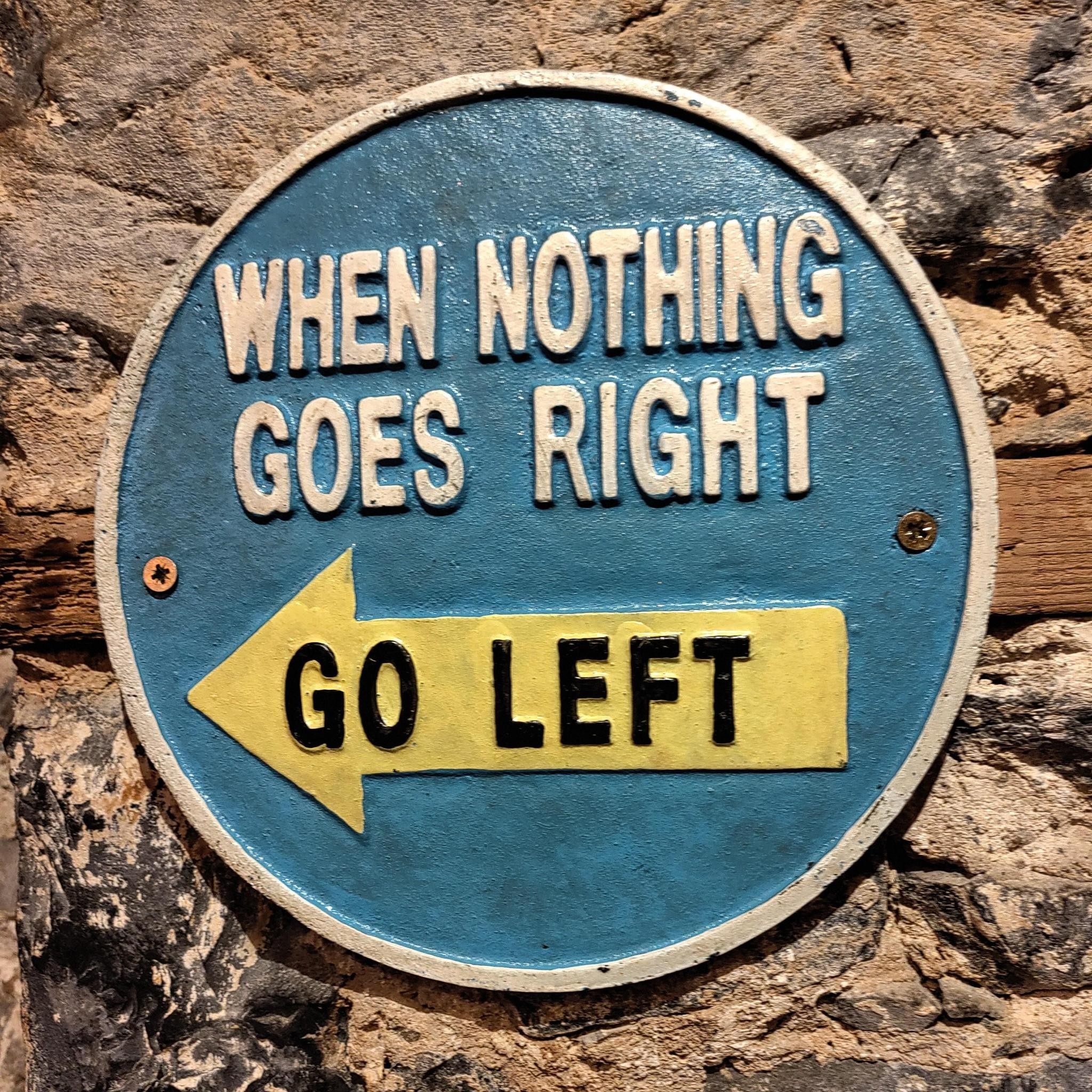 Schild mit der Aufschrift "when nothing goes right go left" mit Pfeil nach links.