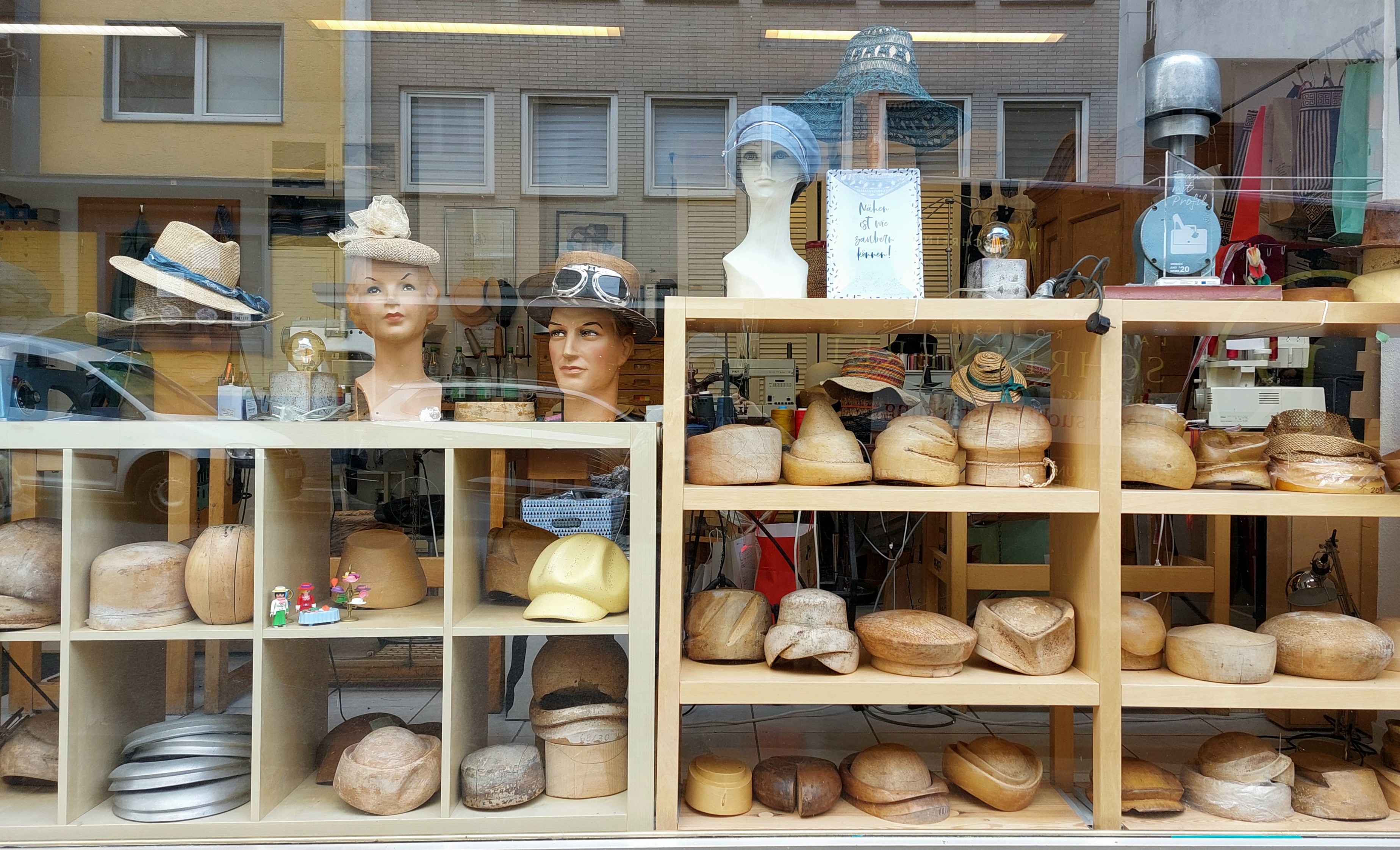 Hutformen im Schaufenster des Hutmachers in der Hindenburgstraße RS. Spiegelung der Fenster der Gegenseite.